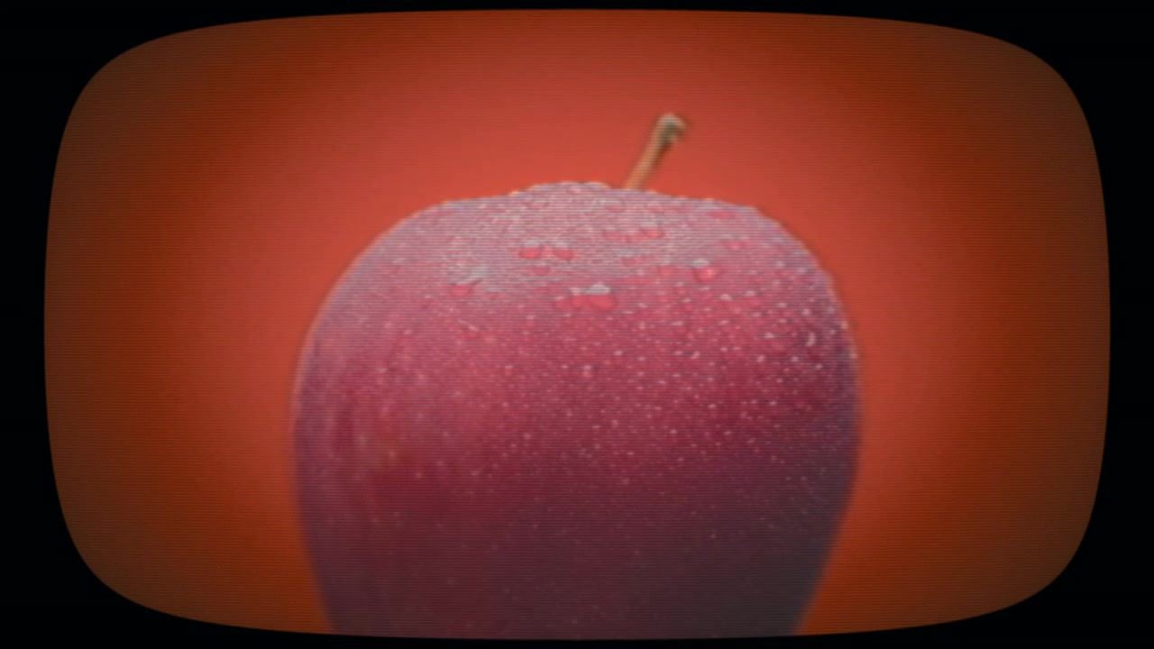 Mela rossa con gocce d'acqua che appaiono e scompaiono. Effetto pellicola vintage.
