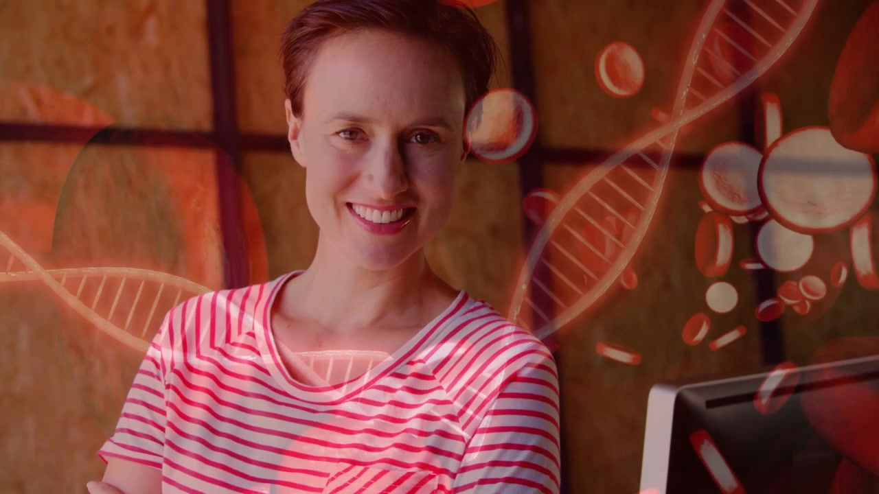 Woman standing in studio, DNA helix drifting from left over face warming tones illustrating biotech