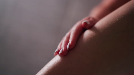 woman touches bare leg in bathroom closeup. lady strokes smooth skin of leg after depilation procedure at home. skincare and spa routine for legs