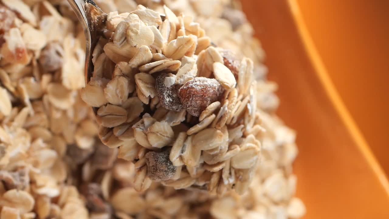 Muesli or Granola Being Scooped and Poured with a Spoon