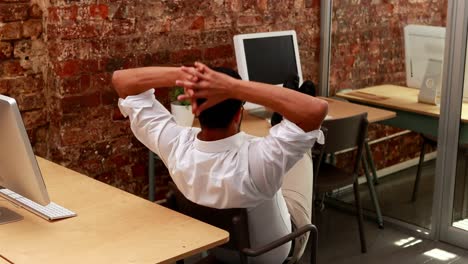 Casual-businessman-relaxing-at-desk-leaning-back