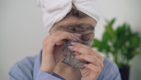 카메라를 보고 안면 마스크를 제거하는 여성의 초상화