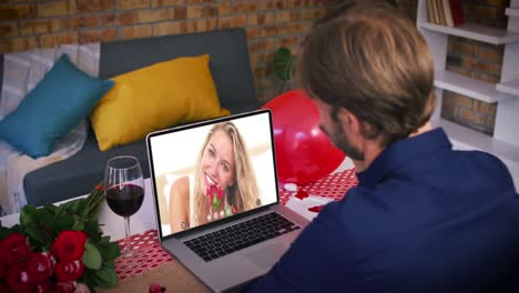 Caucasian-couple-on-a-valentines-date-video-call-man-waving-to-smiling-woman-on-laptop-screen