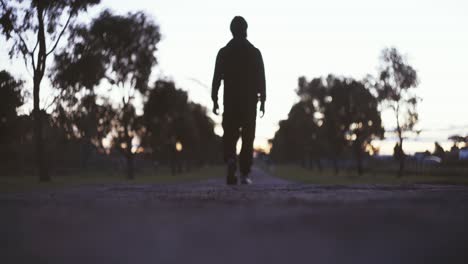 Silueta-De-Un-Hombre-Caminando-Por-El-Camino-Vacío-Durante-La-Puesta-De-Sol