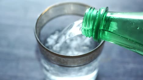 vertiendo un vaso de agua gaseosa con cubos de hielo