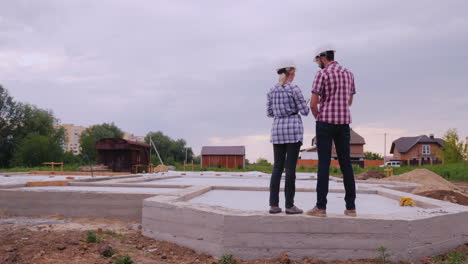 two builders-a man and a woman are on the foundation of the future building discussing the work plan