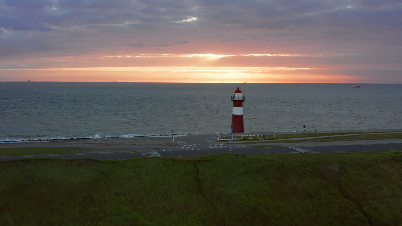 el faro de westkapelle durante una puesta de sol naranja brillante, con mucho viento