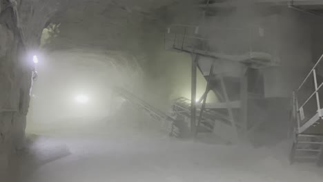 a moving frame capturing salt extraction equipment in a room with high walls and an arch in a salt mine.