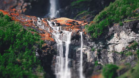 una cascada miniaturizada de dos niveles en los acantilados cubiertos de bosque por encima del lago loenvatnet