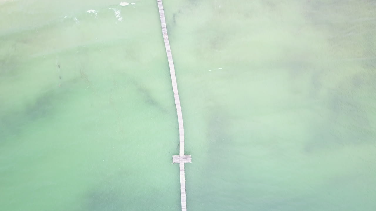 Aerial view of tranquil turquoise water with a T-shaped wooden dock