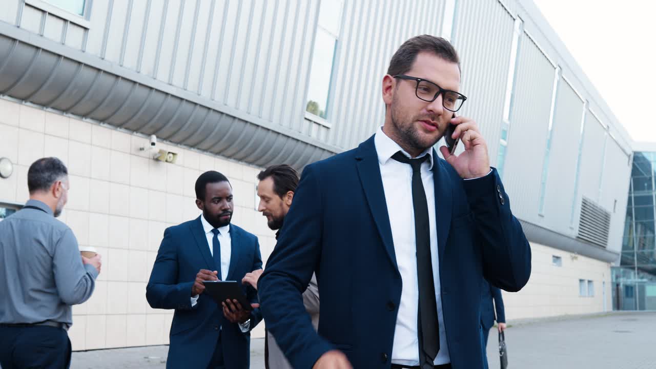 hombre de negocios caucásico con ropa elegante y gafas hablando en el teléfono inteligente en la calle