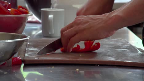 a chef prepares and slices pepper vertically and horizontally to make small chunks in preparation for a restaurant meal