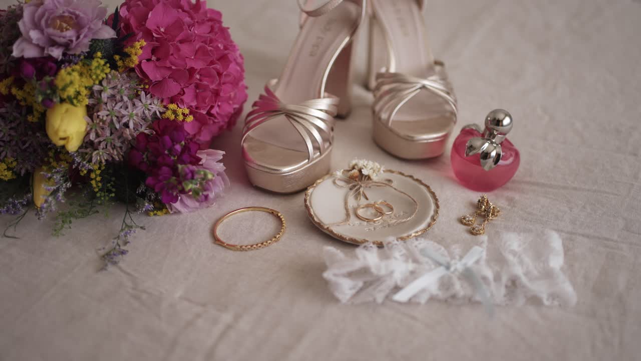 Bridal essentials including wedding rings, gold heels, perfume, jewelry, and bouquet