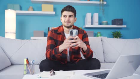 Young-man-watching-video-on-smartphone-alone-at-home.