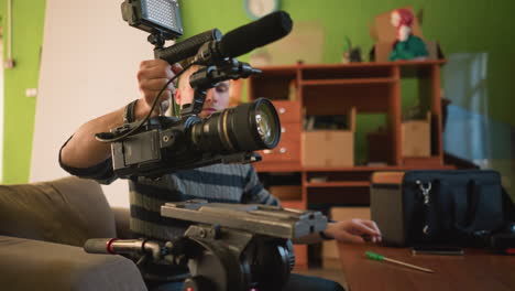 broadcast director adjusting camera and microphone setup in home studio. preparing for video shoot with camera gear and accessories on table, ensuring everything is ready for filming