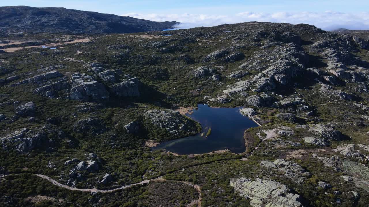 vista aérea orbitando alrededor de un pequeño lago en lo alto de la montaña en serra da estrela portugal