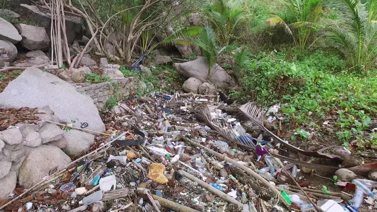 basura masiva no degradable vertida en la jungla cerca de la playa, dronefly que se mueve hacia adelante