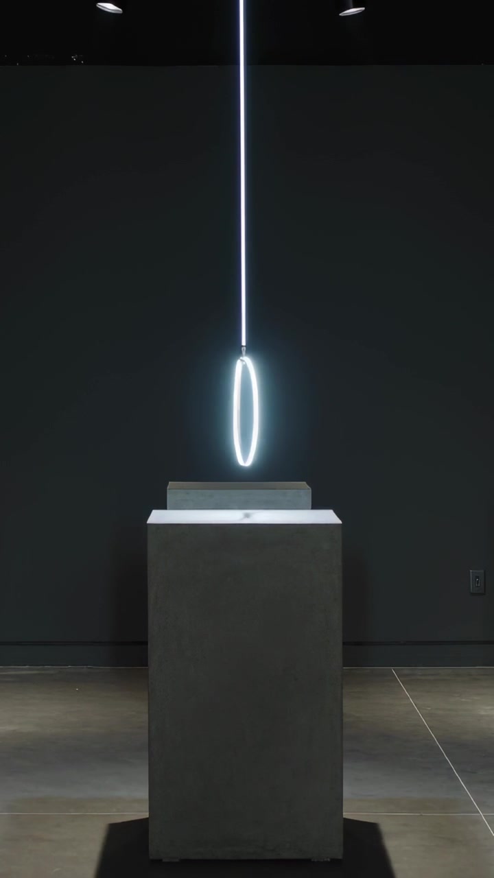 Vertical video: Lowering light rod sending lit ring rotating tilting bobbing over base in gallery