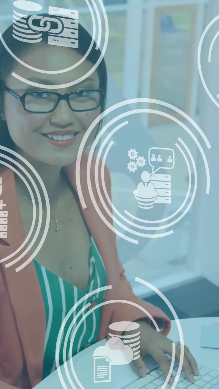 Animation of icon in circles over smiling asian woman working on computer in office