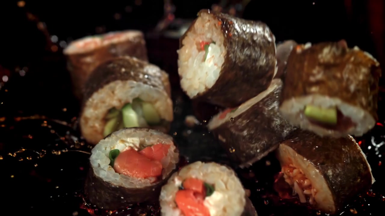 Movimento rallentato di rotoli di sushi fresco che cadono nella salsa di soia