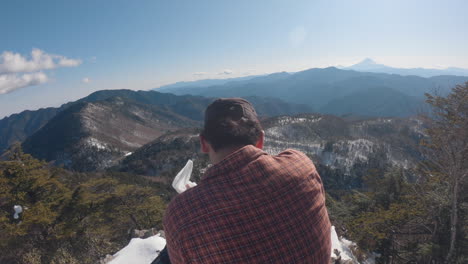 un hombre comiendo en la cima de la montaña