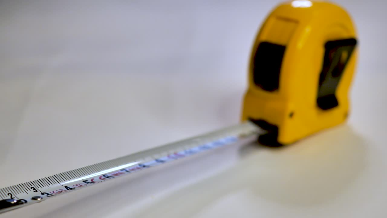 Tape measure. Static shot with changing  focus along the tape measure. Scene B.