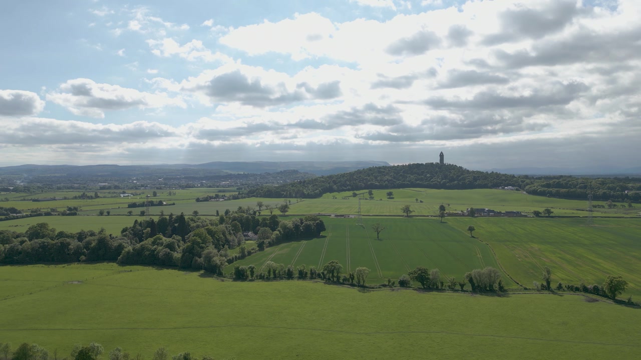 Wide Aerial Ped Down Countryside With Wallace Monument In Background