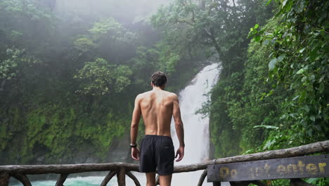 El-Hombre-Camina-Al-Carril-Con-Vista-A-La-Cascada-Del-Río-Celeste-Costa-Rica,-Cámara-Lenta