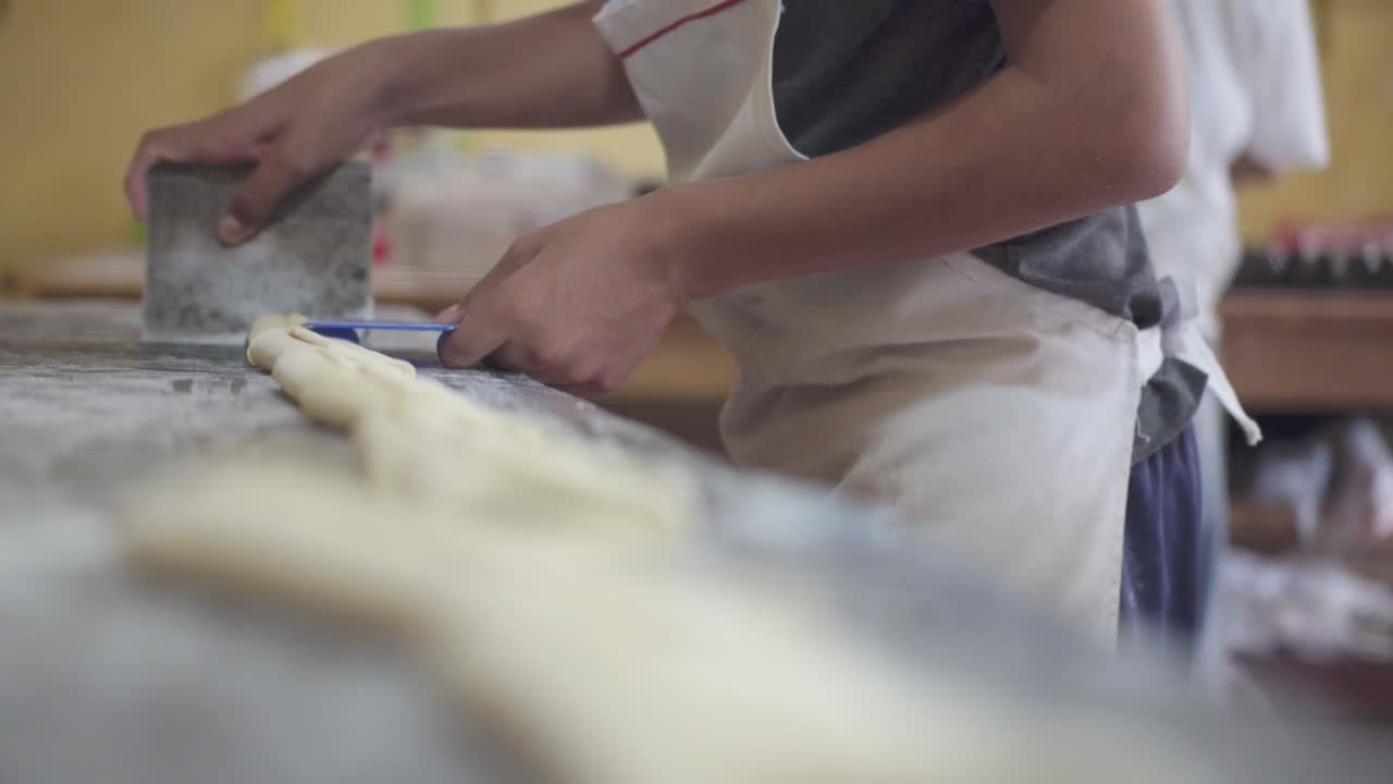 パン作りの準備をしているパスタシェフが作業面でペーストを切断しているクローズアップ