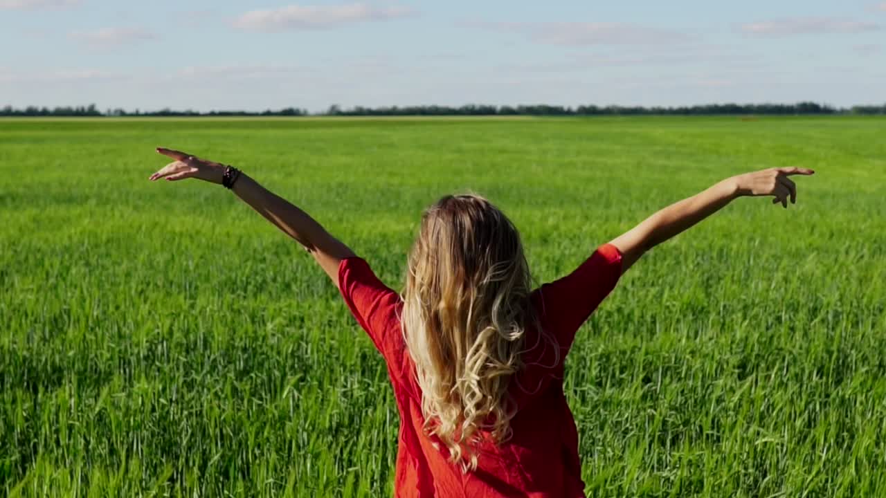 mujer en un campo con los brazos levantados