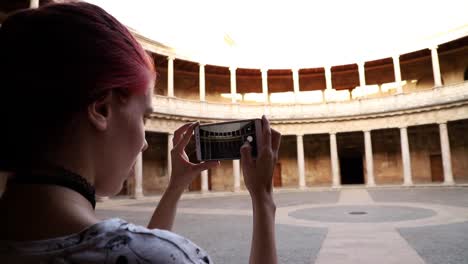 pelirroja haciendo una fotografía con un teléfono inteligente a un monumento en cámara lenta, granada, españa