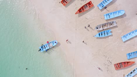 Gruppentourist-Betritt-Ein-Boot-Am-Meeresufer-Für-Eine-Bootsfahrt-Auf-Dem-Karibischen-Meer---Drohnenaufnahme-Von-Oben-Nach-Unten