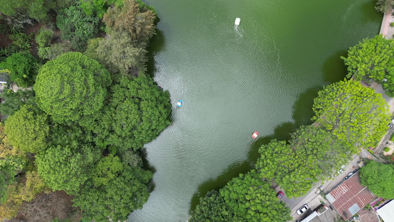 Top-down aerial view of tourists boating on the lake surrounded by lush green trees in Santa Lucia, Honduras, eco-friendly tourism and nature leisure