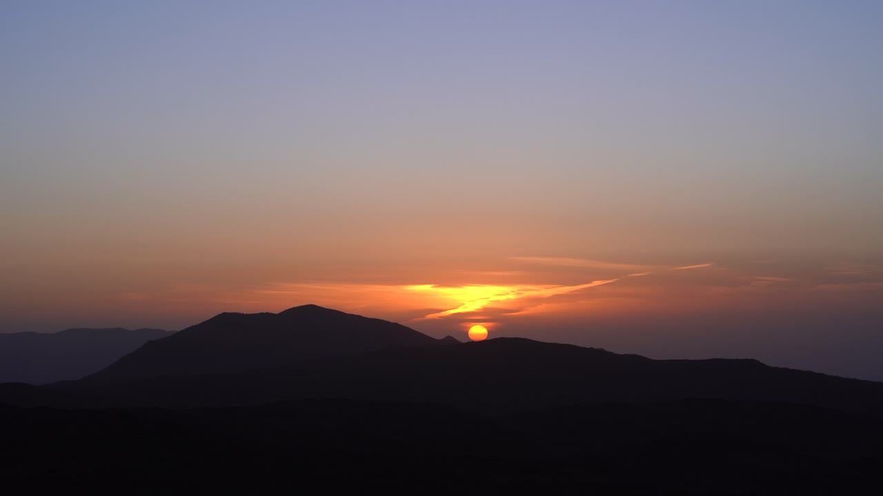 웅장한 산 뒤에 빛나는 일몰의 놀라운 항공 타임  ⁇ 스 4k 숨가 ⁇ 는 하늘 색상과 평화로운 산의 실루 ⁇