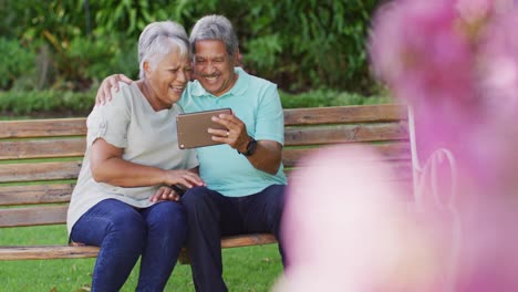 Video-De-Una-Feliz-Pareja-Birracial-De-Ancianos-Usando-Una-Tableta-En-El-Jardín