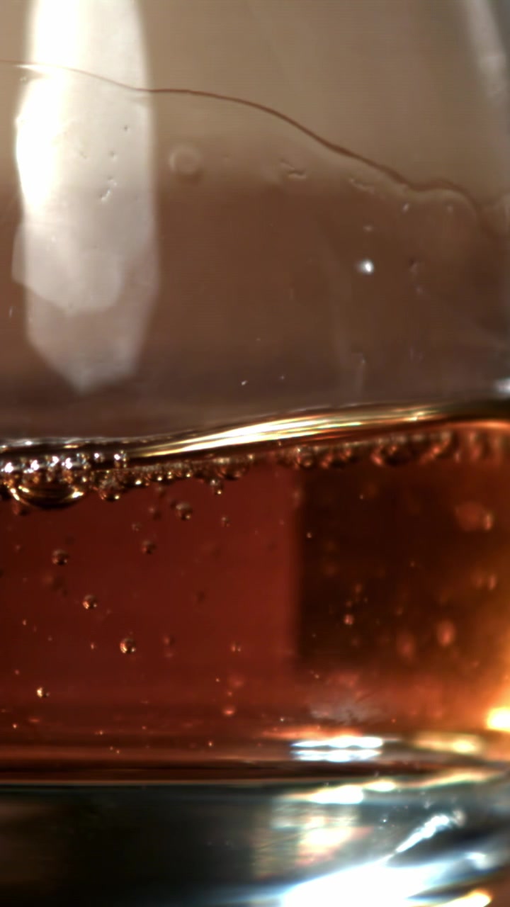 Primo piano di una bevanda marrone frizzante in un bicchiere