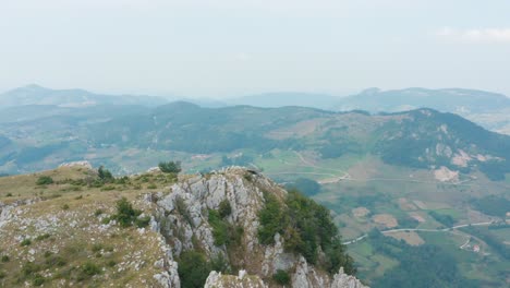 rocky european mountain summit overlooking countryside valley, aerial arc shot