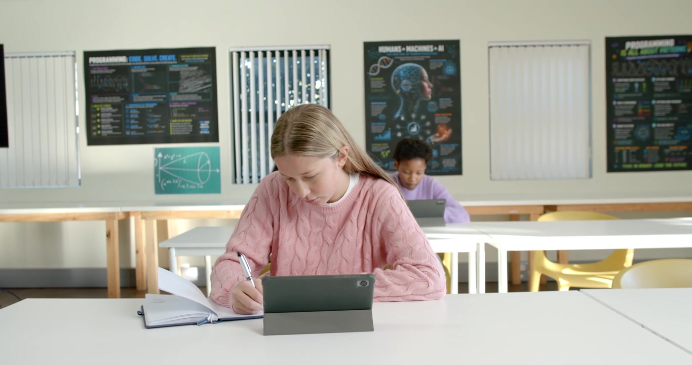 Studentesse di diverse etnie che studiano in classe, con l'adolescente in primo piano che segue il tablet e prende appunti