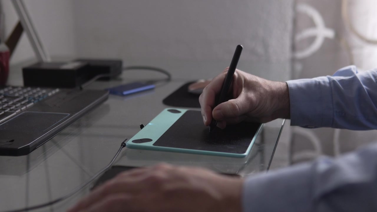 Man using a graphic tablet for digital design. Artist drawing on a laptop computer at his home office.Digital signature of a business owner signing contracts and term sheets
