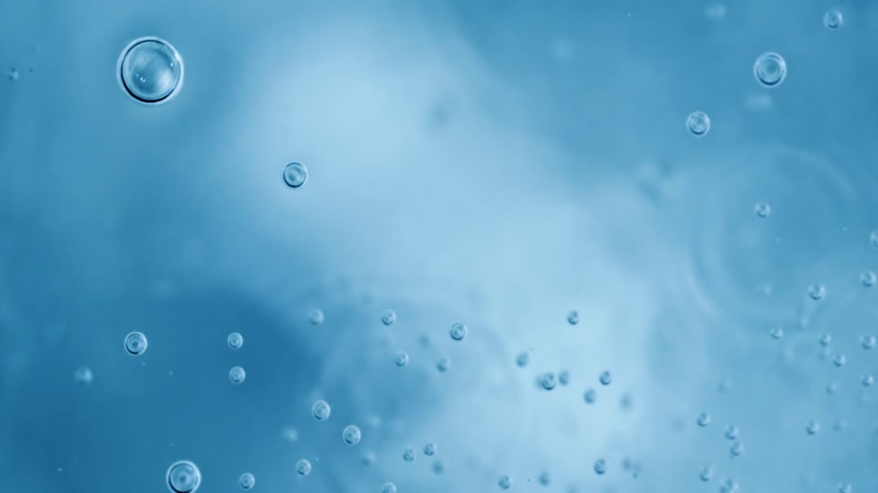 Oxygen bubbles in water on a blue abstract background on super slow motion.