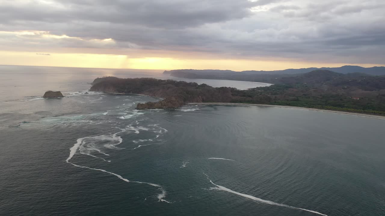 Avvicinamento alla costa della Costa Rica dall'Oceano Pacifico al tramonto con penisola rocciosa, ripresa aerea in sorvolo