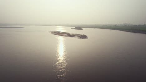 Vista-Aérea-De-Ensueño-Del-Reflejo-De-La-Luz-Del-Sol-En-El-Fangoso-Río-Chenab-En-Pakistán