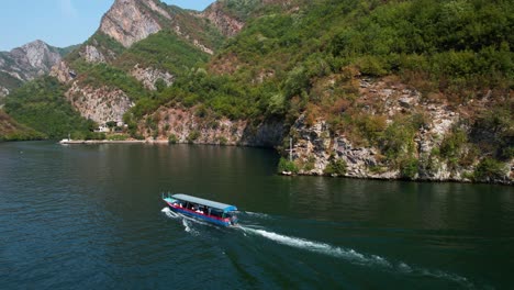 tourists on boats sailing through alpine valley on shala river, near popular traditional guesthouses