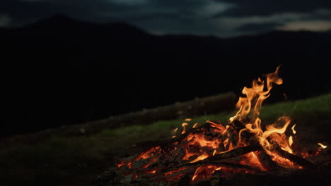 closeup camp fire burning in dark evening night mountains landscape nature.