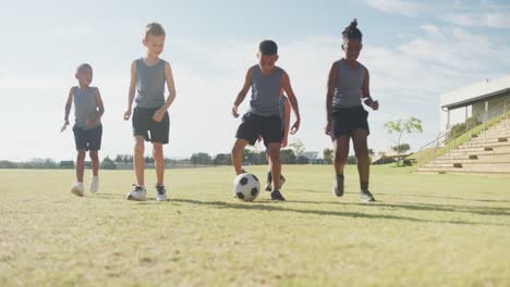 video de niños felices y diversos jugando al fútbol en un campo deportivo