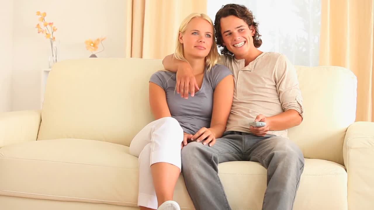 소파 에 앉아 tv 를 보고 있는 즐거운 부부