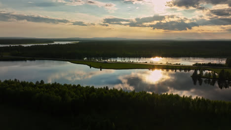 Aerial-view-of-a-sunset-reflecting-from-a-lake-in-Lapland,-summer-evening