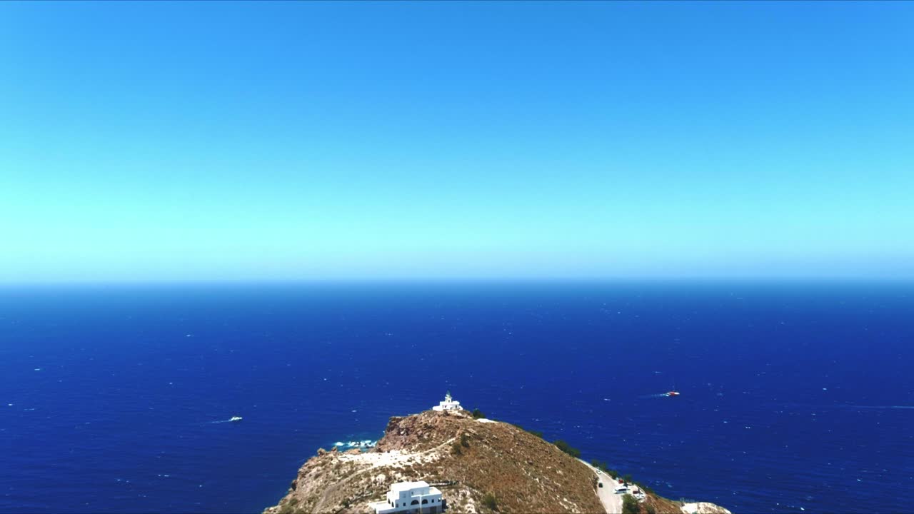 그리스 산토리니의 아름다운 언덕에 있는 아크로티리 등대 위로 공중 4k 푸른 바다와 하늘 꼭대기 전망
