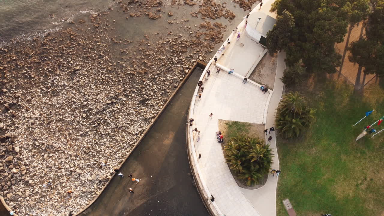 espectáculo aéreo de arriba hacia abajo que muestra la playa rocosa con el río en el edificio torre belem en un día soleado