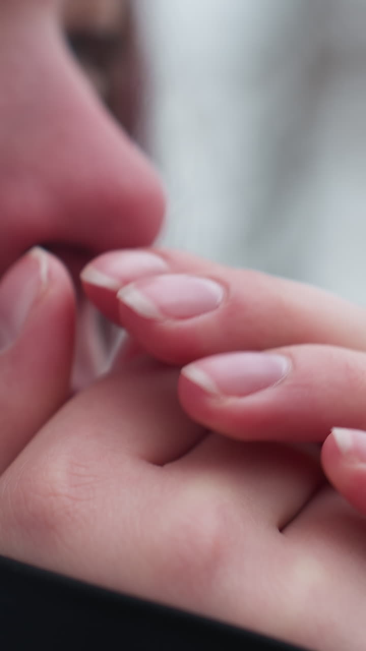 vista de cerca del rostro de una mujer joven que siente frío en invierno, frotándose las manos para calentarse, nariz roja y piel seca resaltan las duras condiciones climáticas, el fondo borroso de árboles desnudos mejora